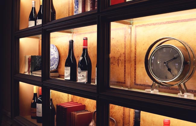 Vitrina retroiluminada com garrafas de vinho, pratos e livros